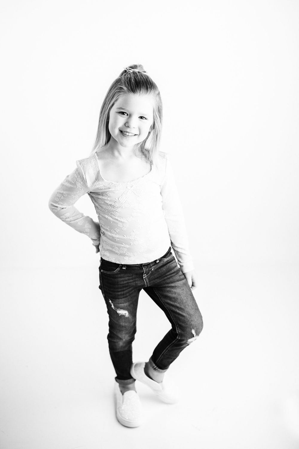Three black and white photos show a child in a white shirt and jeans jumping and playing against a white background.