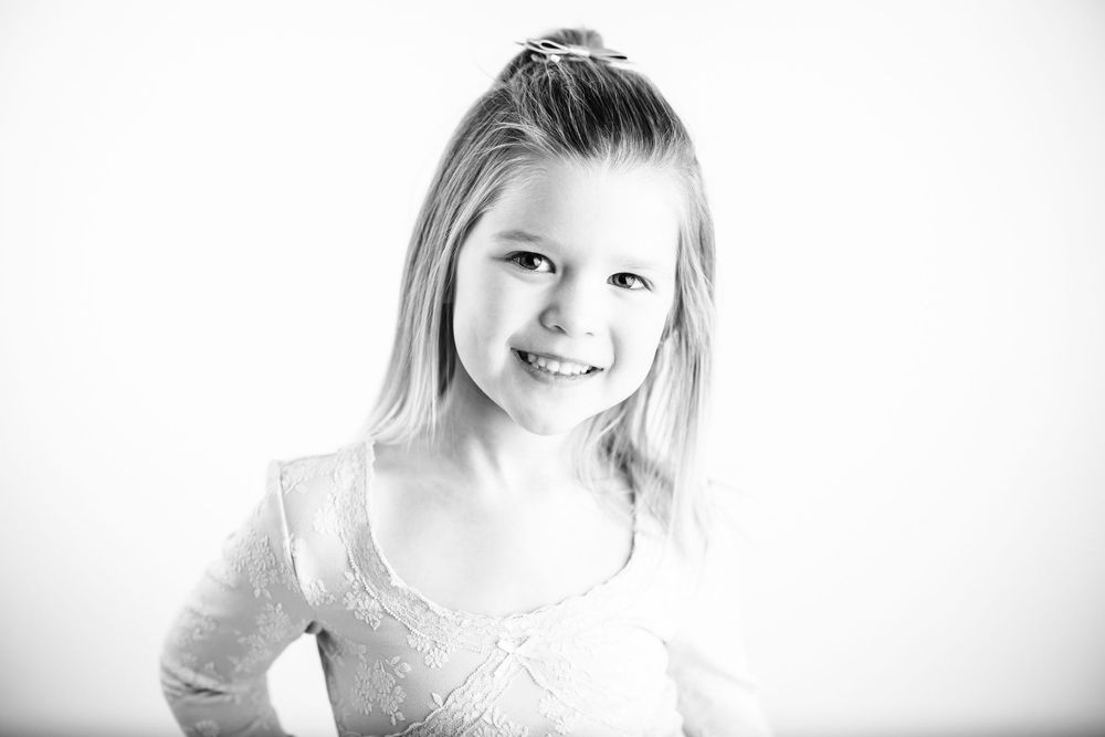 Black and white portrait showing a bright smile against a light background.