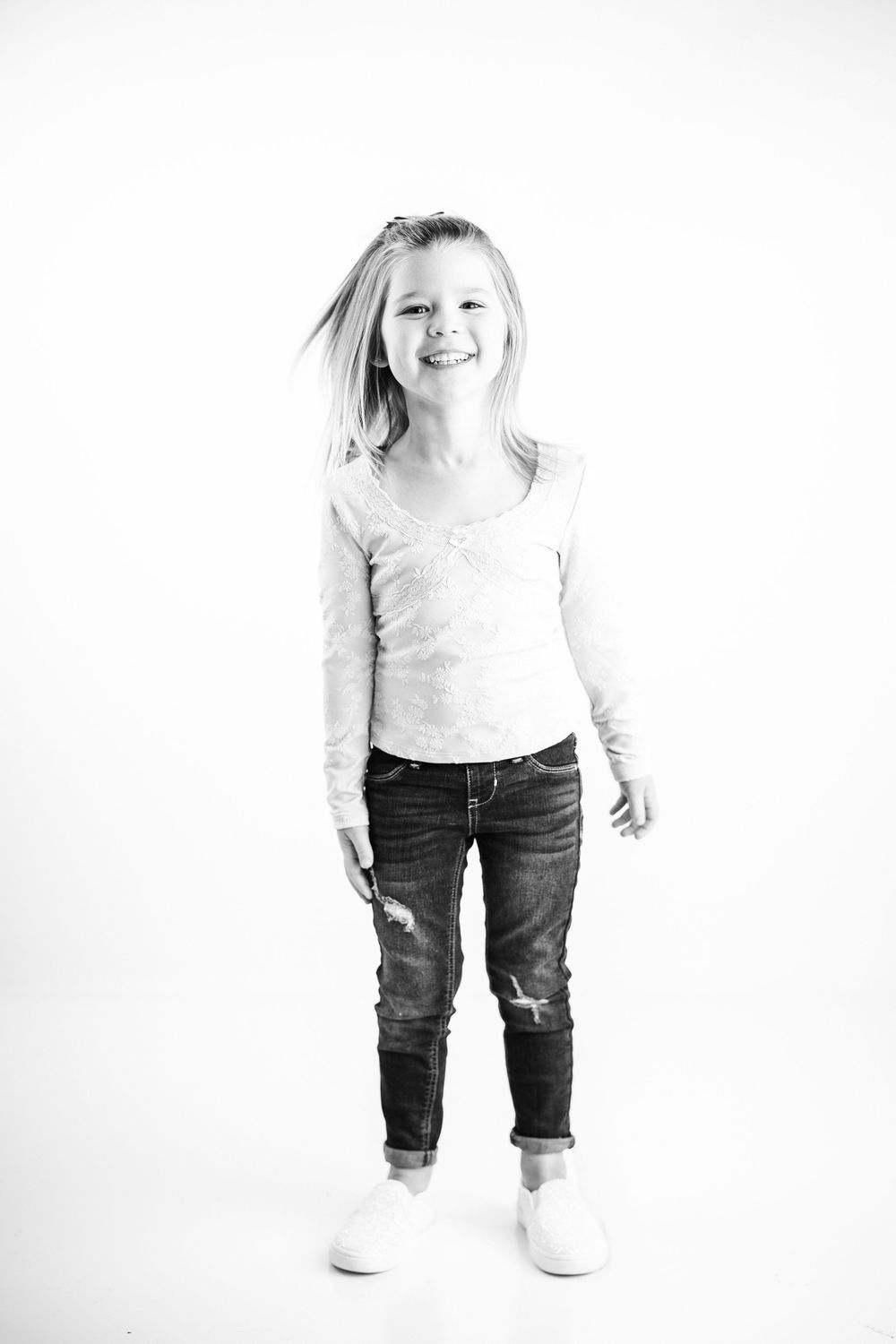 A sequence of black and white photos showing a toddler in jeans and a light top standing against a white background.