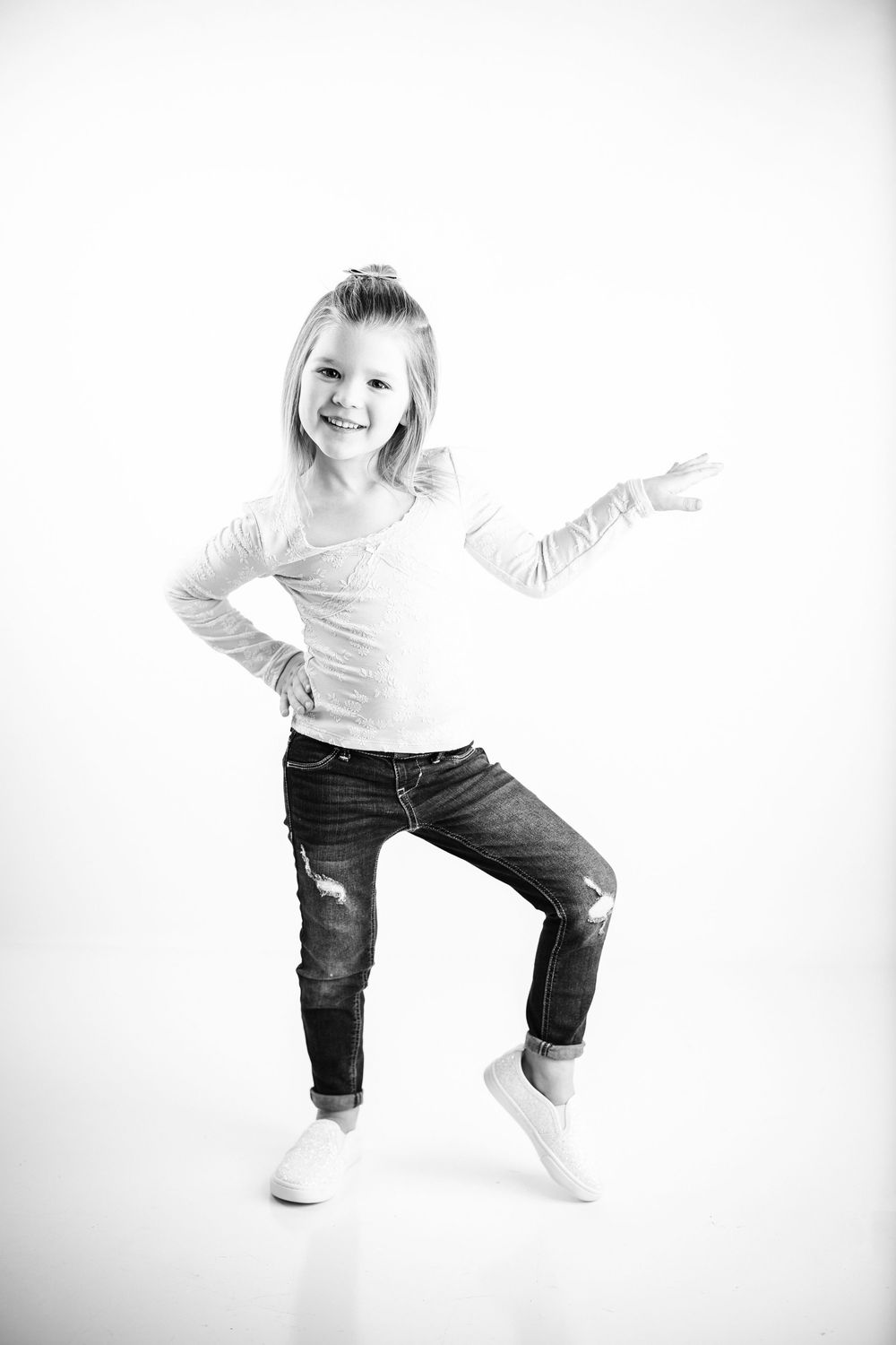 Dynamic black and white photos capture a child in casual wear jumping and playing against a bright white backdrop.