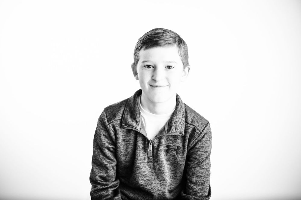A series of four black and white portraits showing the same person in different poses against a light background.
