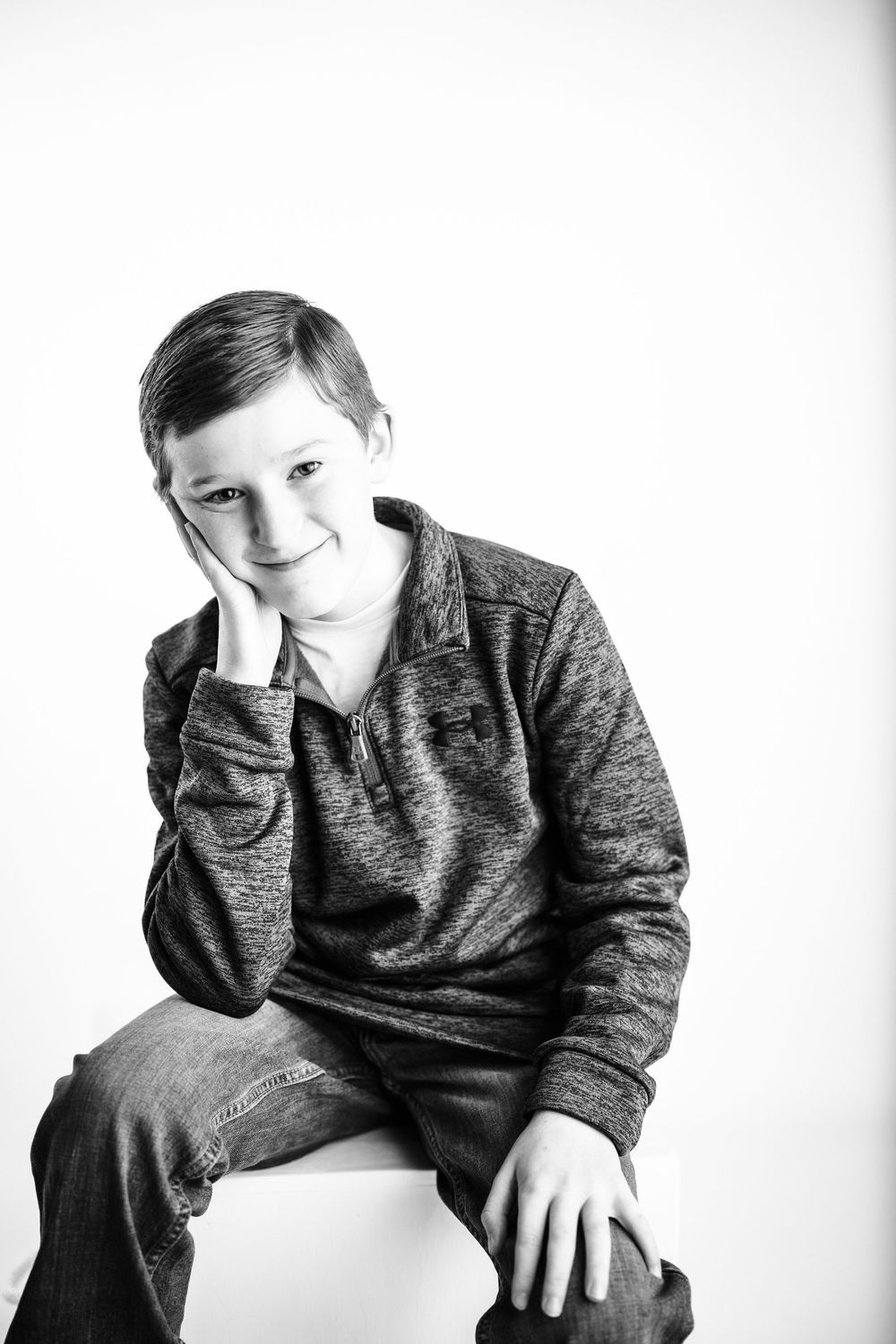 Black and white portrait series of a young child in a dark sweater posing with different expressions.