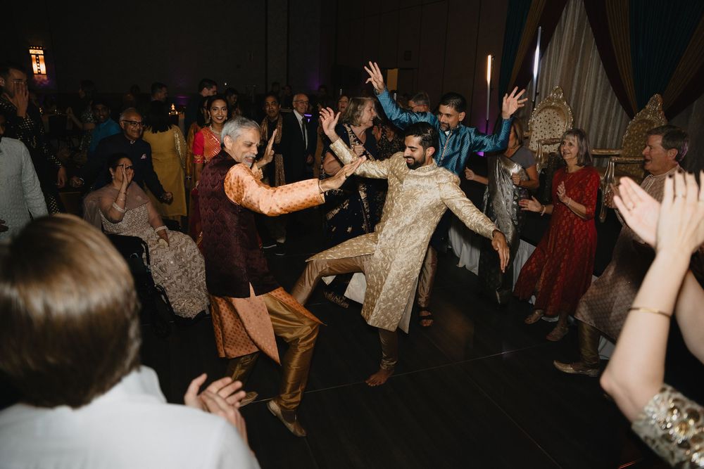 Energetic wedding guests in colorful Indian attire dance together on the reception dance floor.at Sandia Resort and Casino