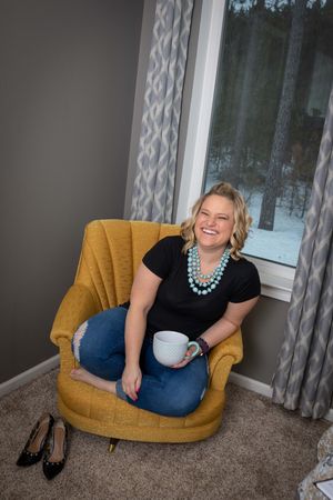 A cozy yellow armchair sits by a window with gray patterned curtains in a modern room setting.