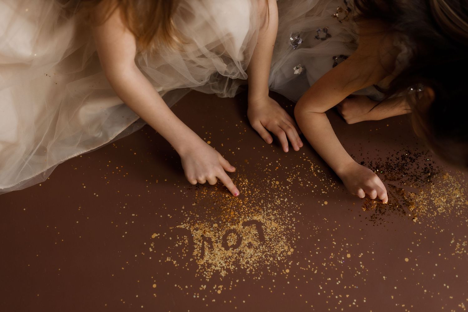 Bare feet with glittery gold sparkles scattered on a dark brown wooden floor.