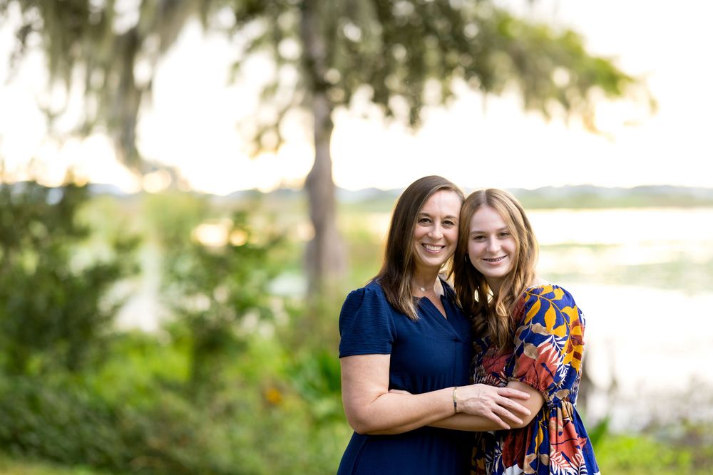 Two people in coordinating navy and floral outfits pose together outdoors during a photo session.