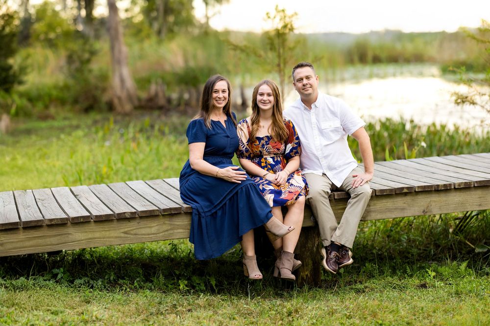 Family sitting together on a wooden boardwalk in a natural outdoor setting during golden hour.