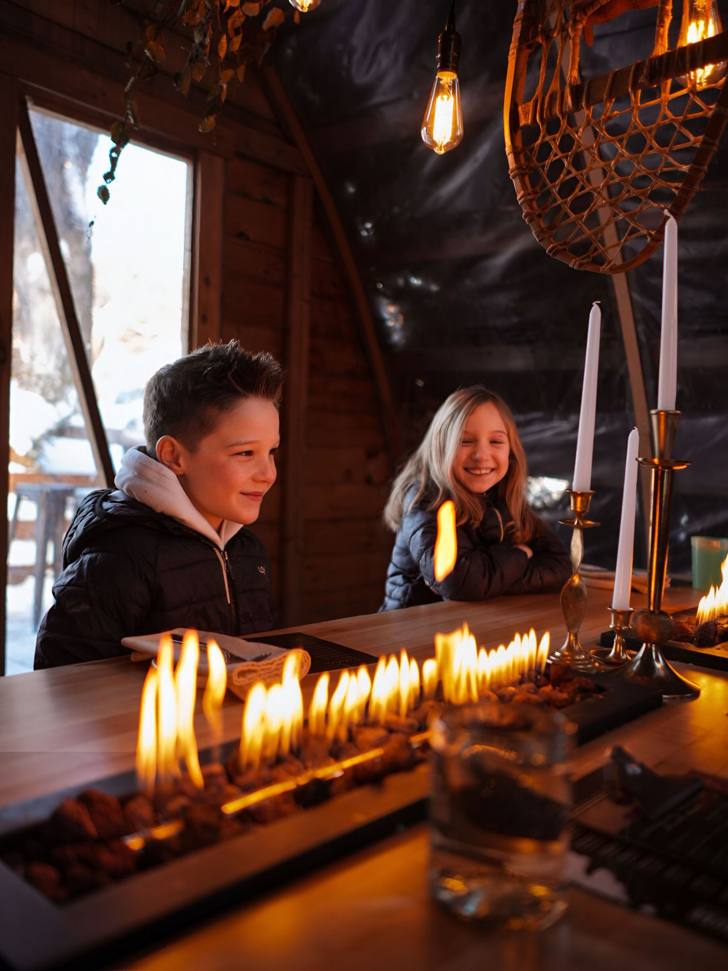 Lit candles glow in a dark wooden interior creating a warm atmospheric ambiance.