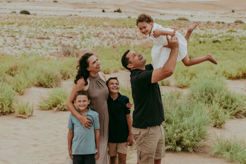 Parents and children playing together on golden dunes under clear blue sky