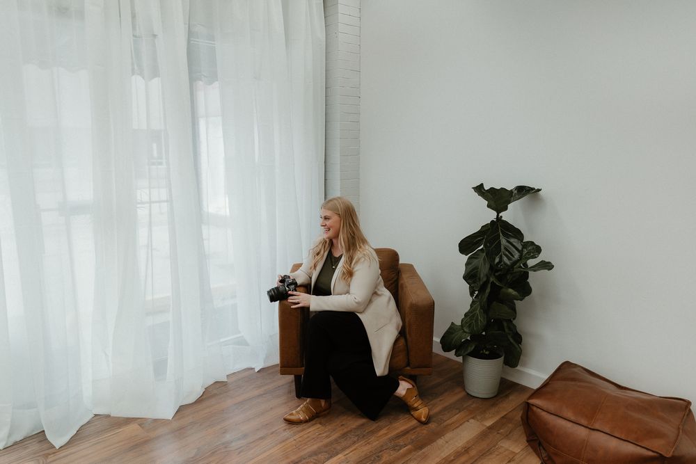 Person lounging on leather couch in modern living space with potted plants and natural lighting.