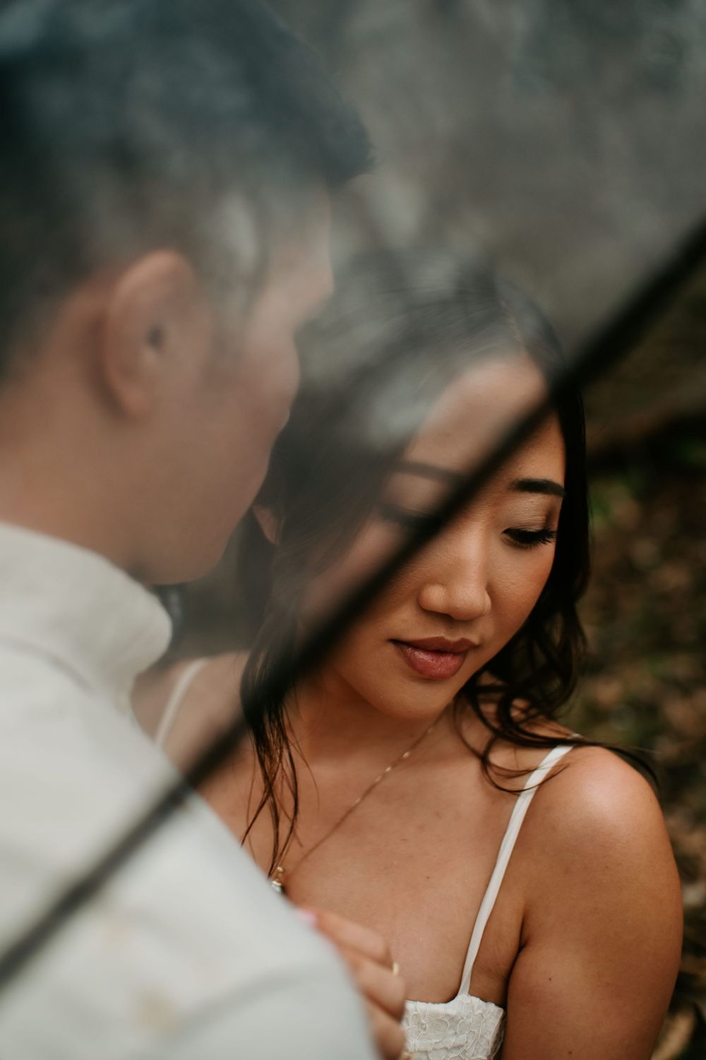 Intimate wedding portrait captured through glass with soft lighting and romantic mood.