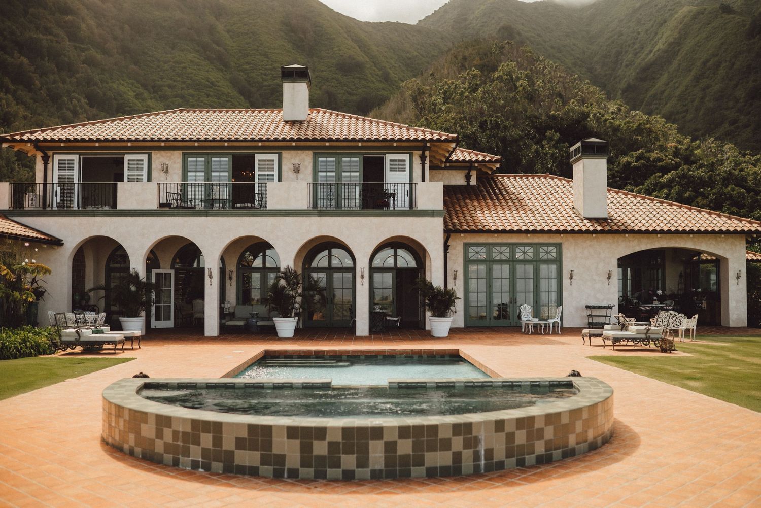 Modern Spanish-style venue with arched windows and pool area surrounded by mountains.