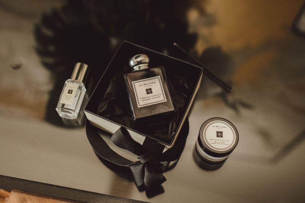 Collection of perfume bottles and wedding accessories arranged on a dark surface.