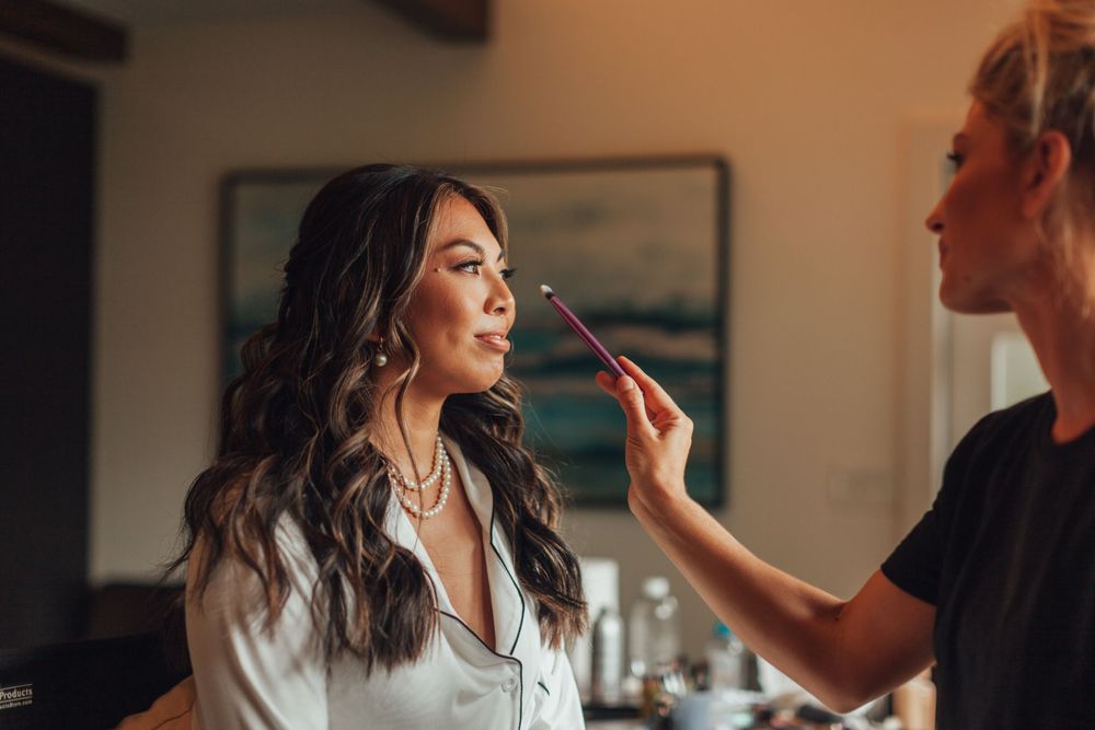 Wedding preparation scene showing makeup application in a softly lit indoor setting.