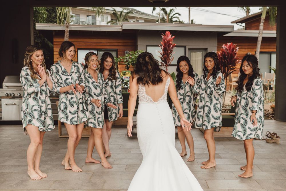 Bridesmaids in matching floral print dresses standing together at an outdoor wedding venue.