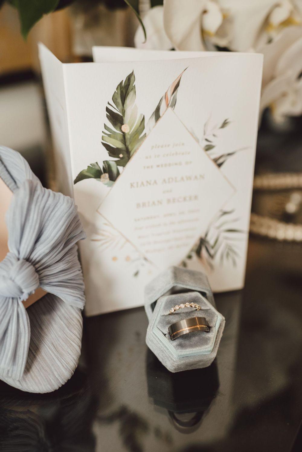 Wedding stationery and rings arranged with delicate gray ribbon details and botanical designs.