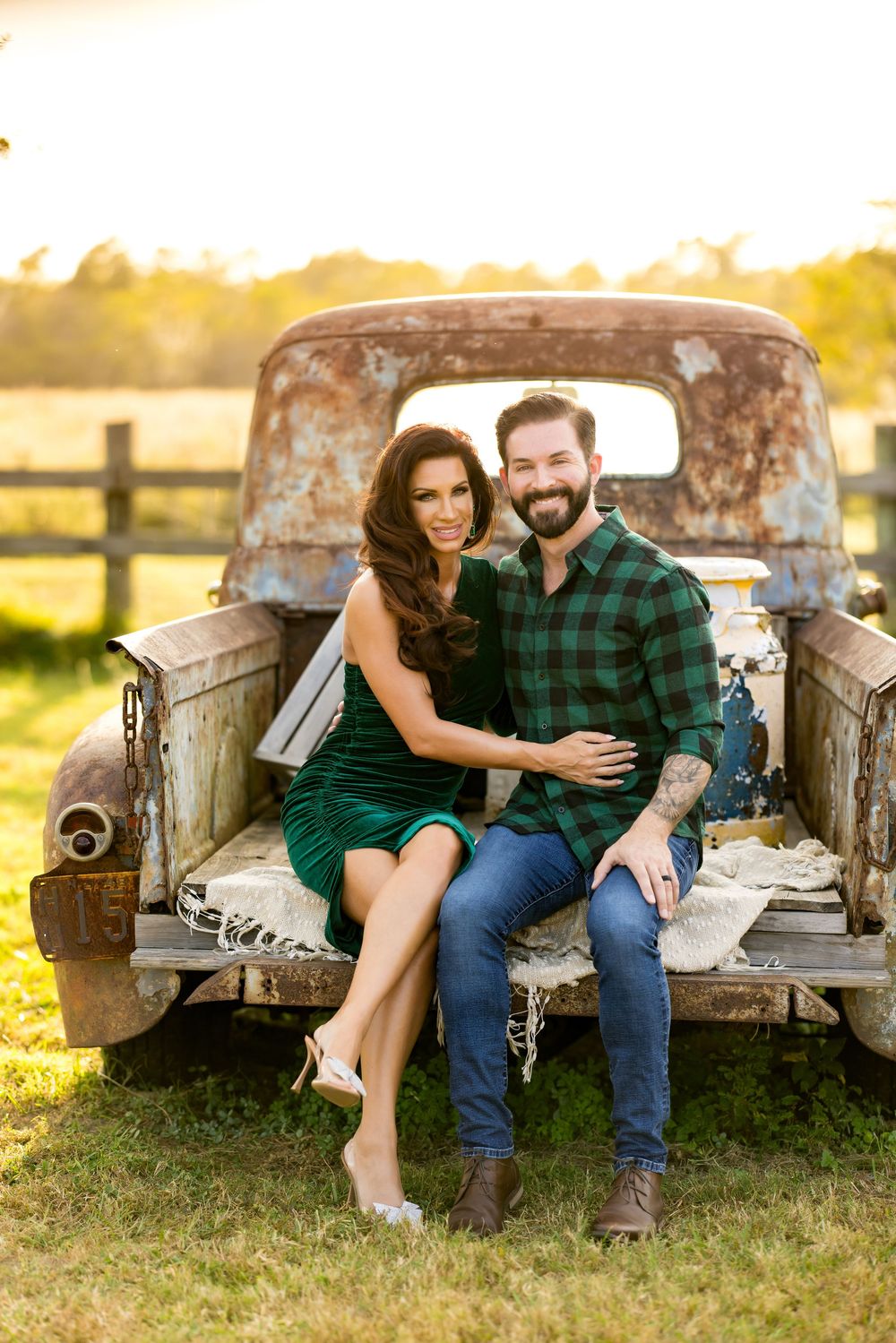 A romantic couple poses together on a rustic vintage truck tailgate during a golden sunset photoshoot.