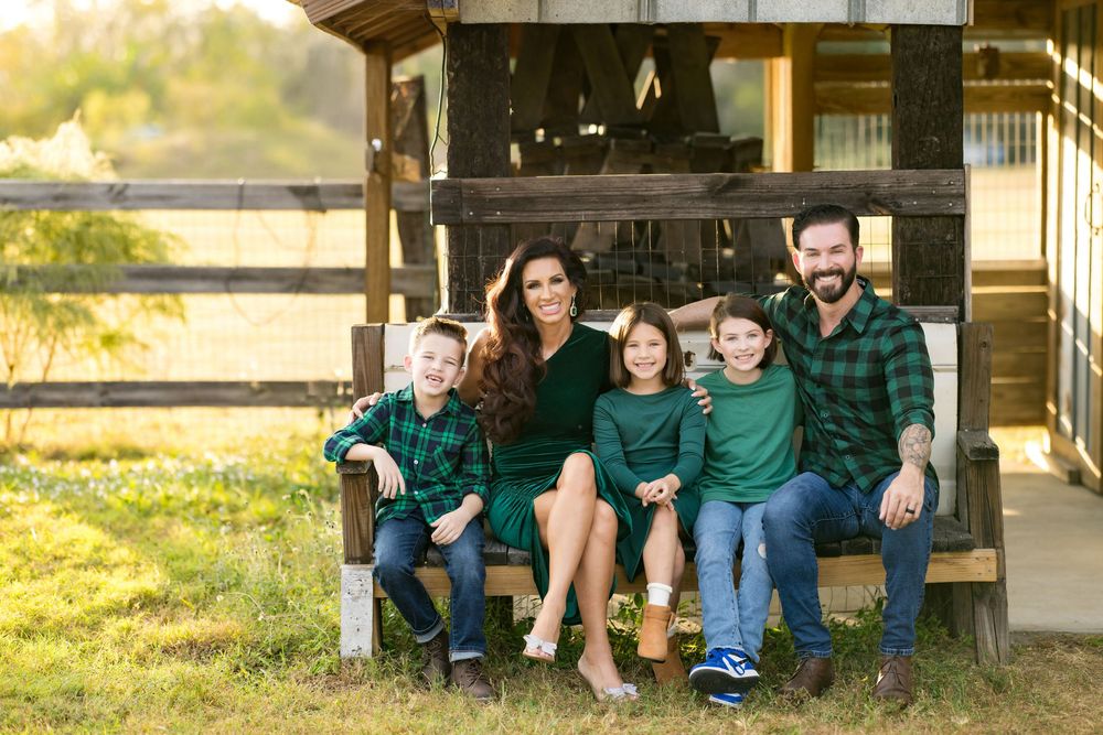 A group sits together on wooden steps at sunset, creating a warm and intimate family portrait in casual attire.