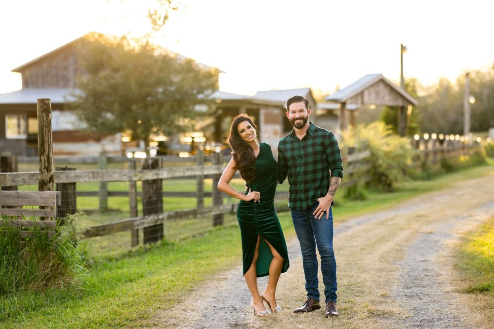 A couple walks hand in hand down a gravel path at sunset on a rustic farm property.