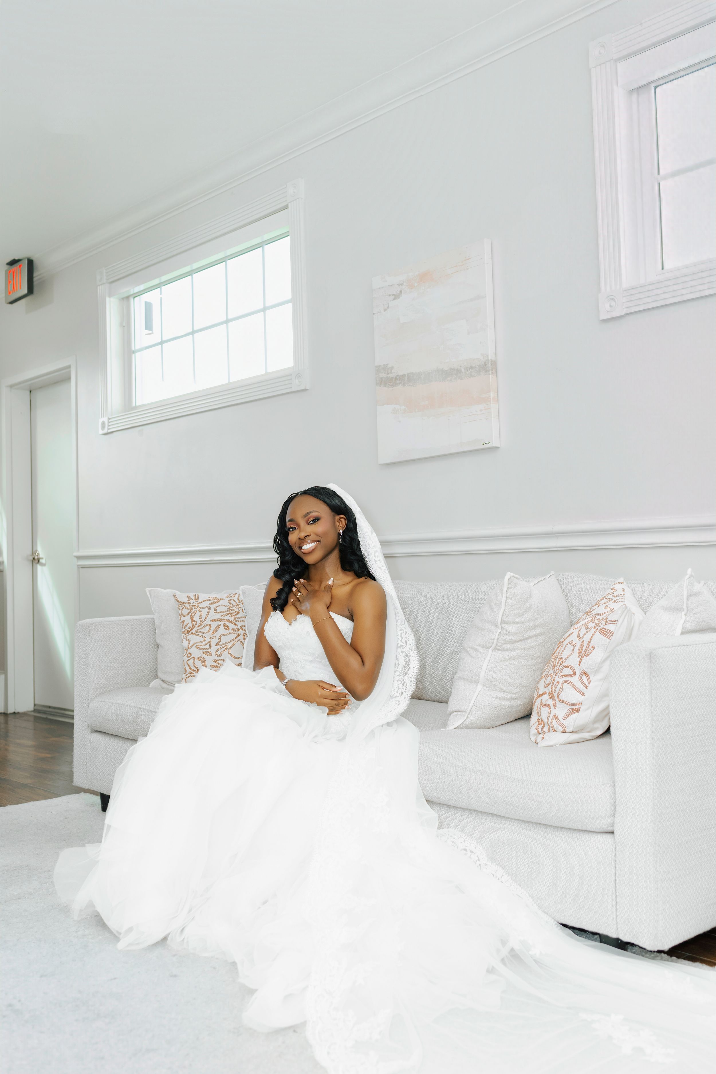 An elegant bridal portrait session in an all-white room with plush furniture and natural lighting.