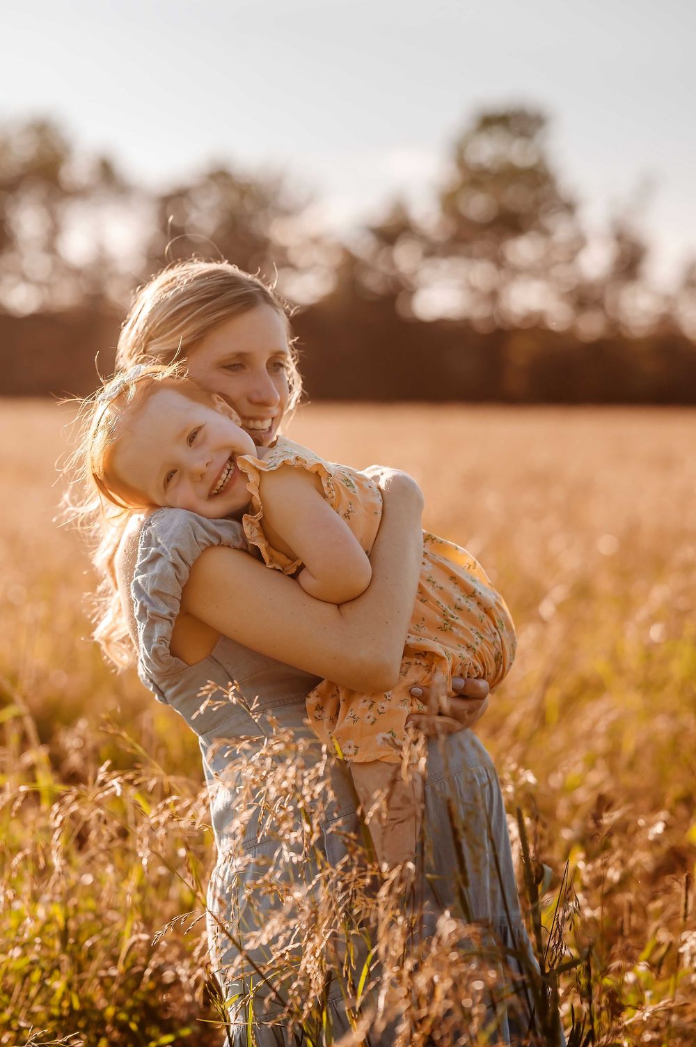 A tender moment between parent and child embracing in a sunlit field at golden hour.