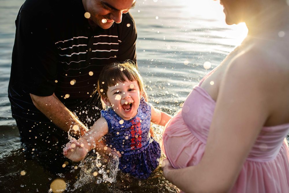 Playful family moment splashing water at sunset by the lake.