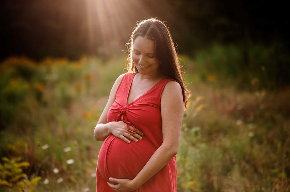Artistic maternity portraits with dramatic lighting in a natural outdoor setting.
