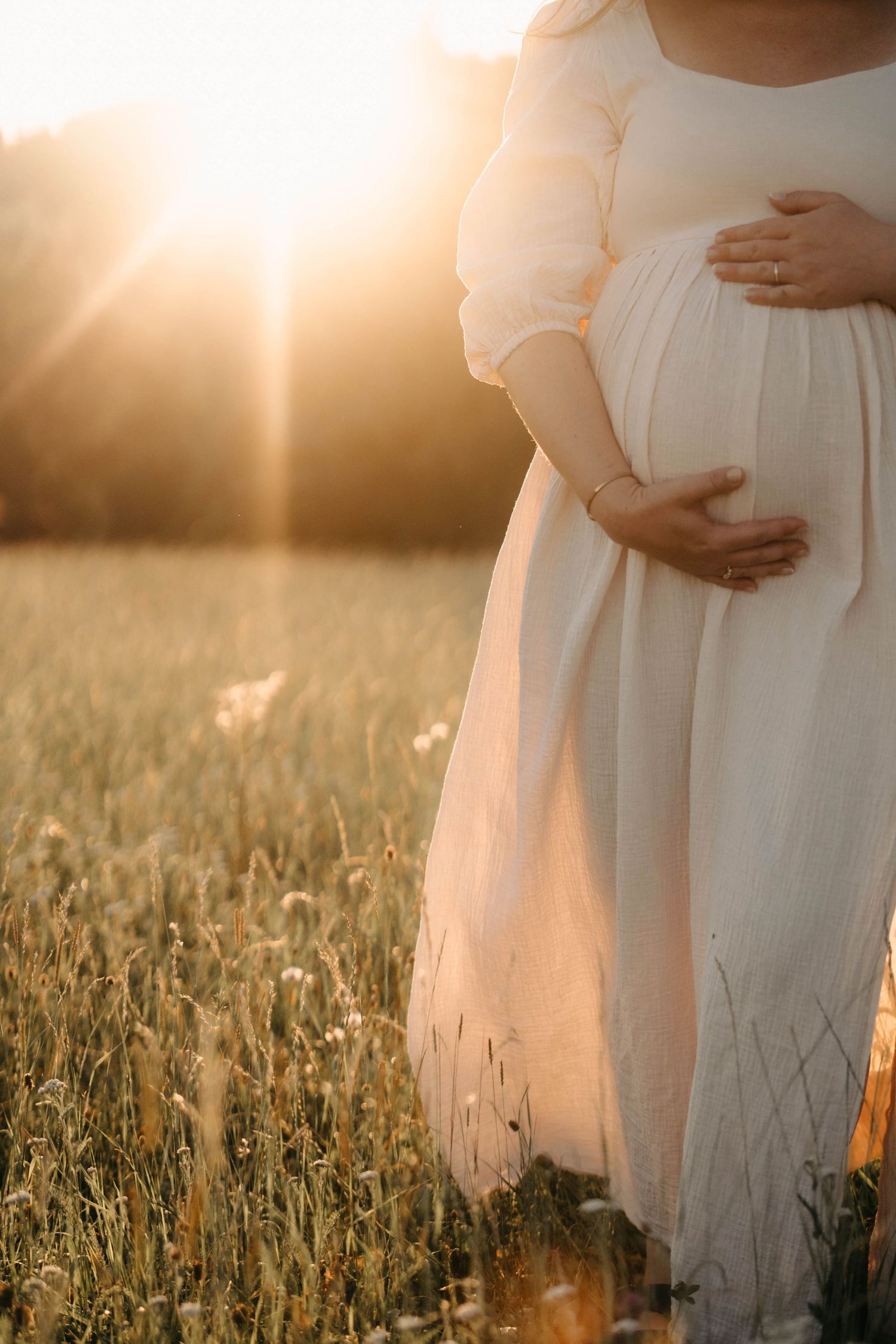 Babybauchshooting im Sonnenuntergang mit werdendem Vater und Mutter