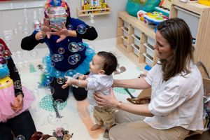Children and teachers engage in sensory play activities with colorful materials in a classroom setting.