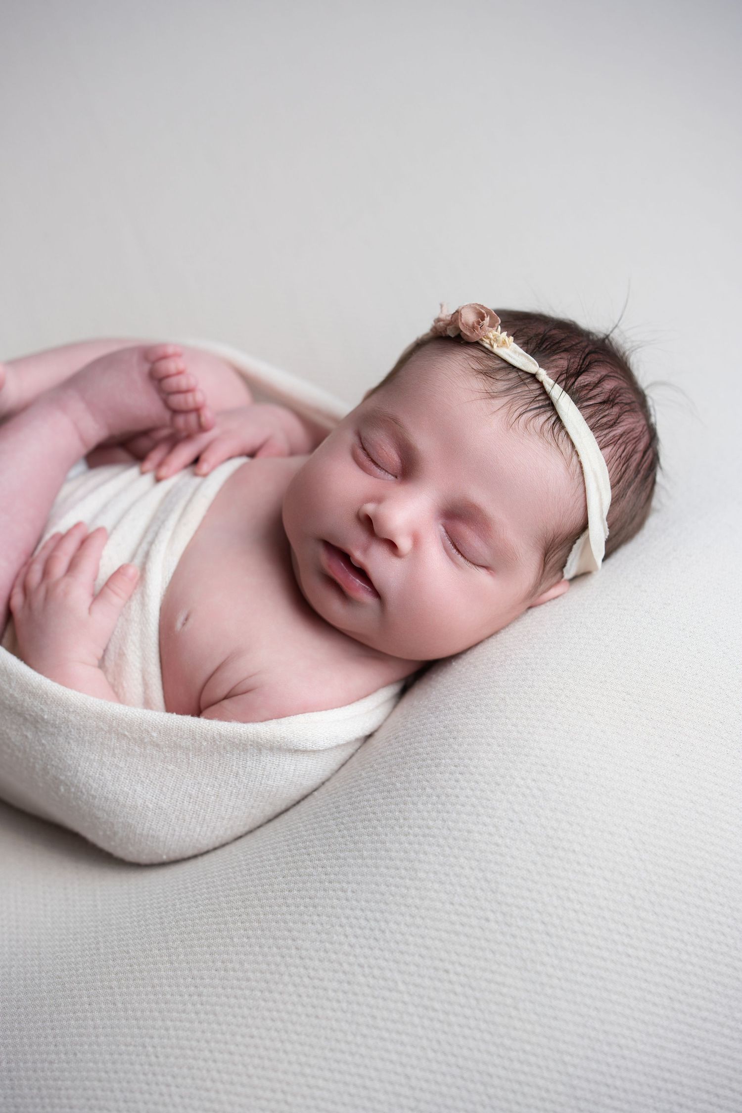 Newborn baby girl wrapped in womb pose sleeping peacefully during newborn photography session
