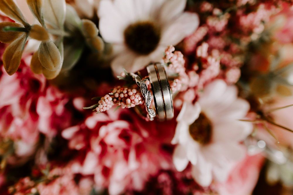 Pink cherry blossoms and white daisies create a dreamy floral arrangement with soft bokeh effect in natural light.