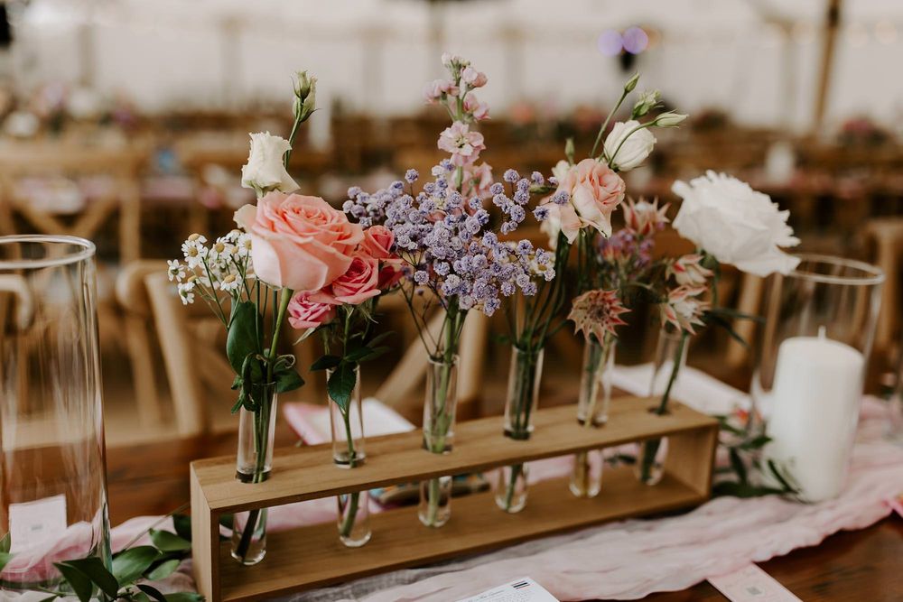 Wedding reception table decorated with delicate floral arrangements in glass vases and soft pink table runners.