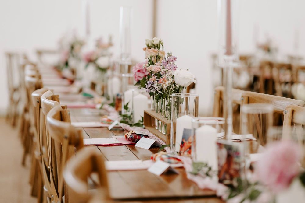 Elegant wedding reception tables decorated with pink floral centerpieces and white linens in a bright banquet hall.