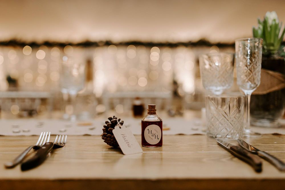 Elegant wedding reception table settings with crystal glasses and white linens in warm ambient lighting.