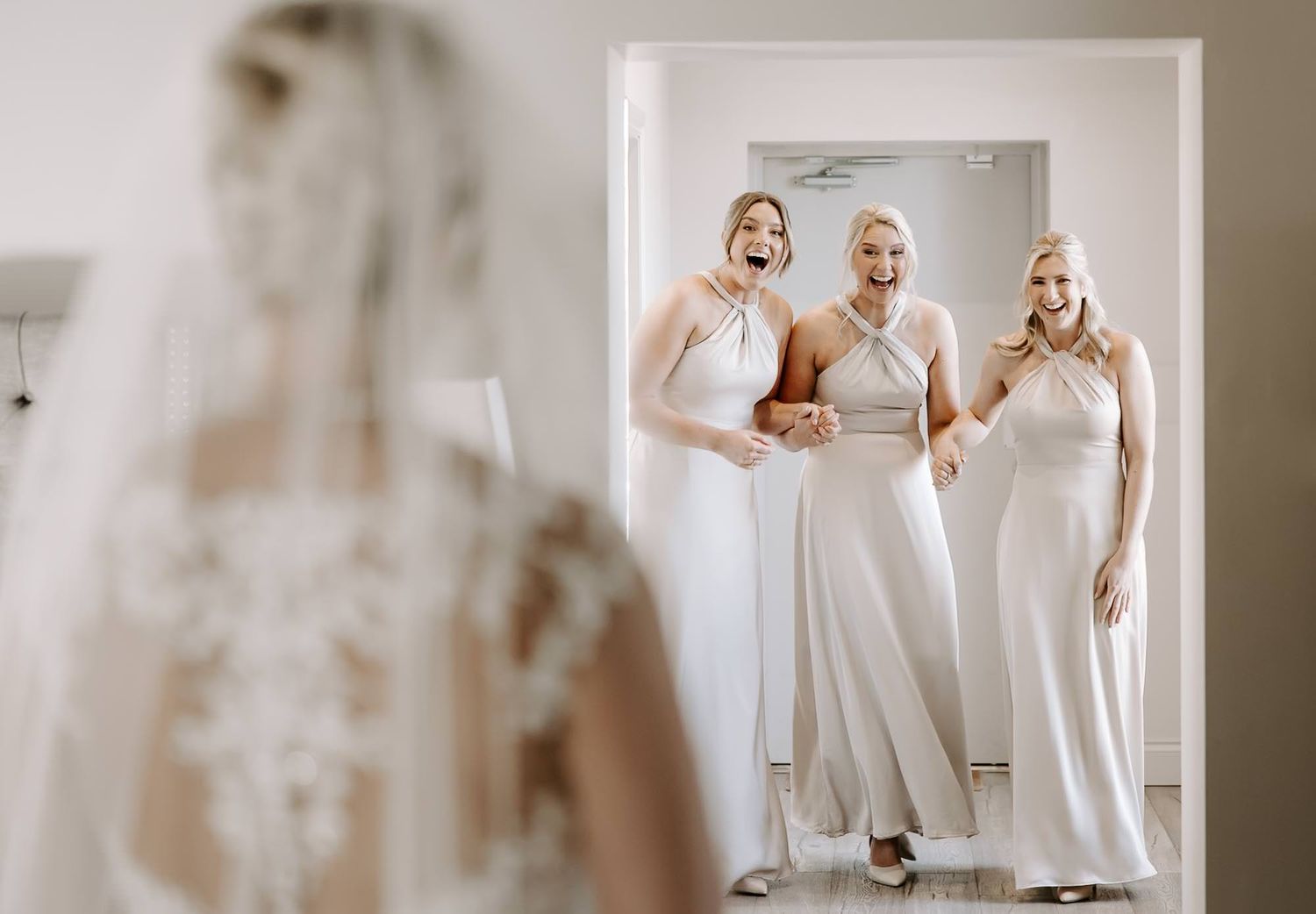 A row of elegant white wedding dresses displayed in a bridal boutique with soft natural lighting.