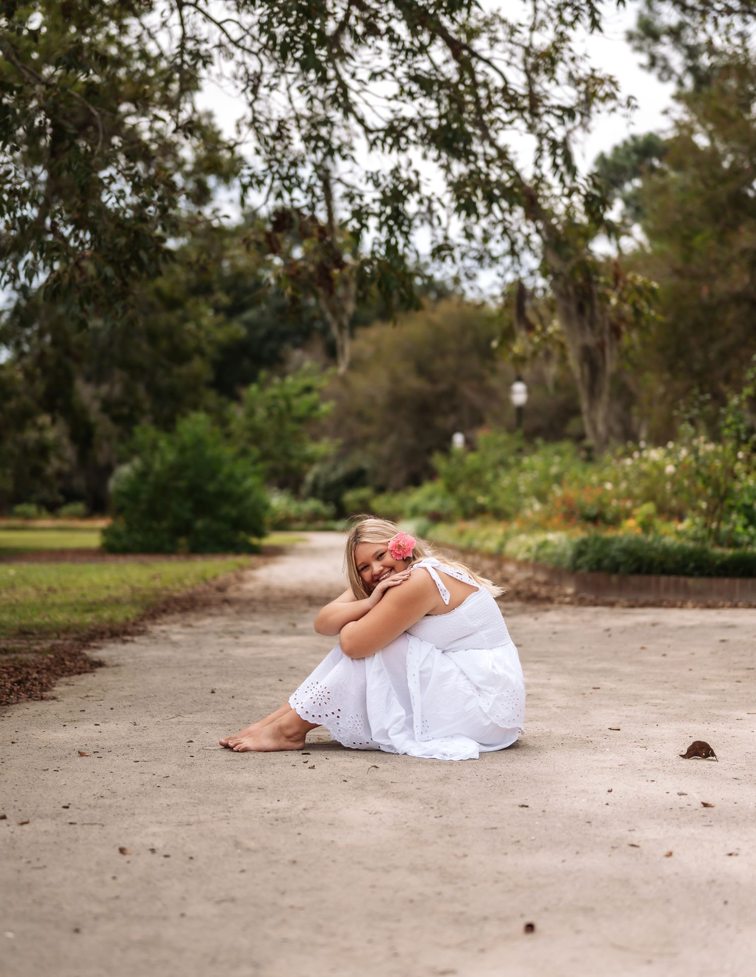 A series of artistic photos showing a figure in white dress reclining on a dirt path through a wooded area.