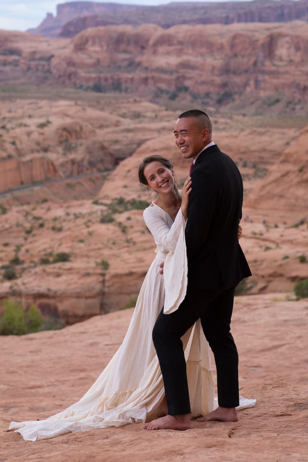 A couple shares intimate moments against the stunning backdrop of red rock canyons and desert cliffs during a sunset photoshoot.