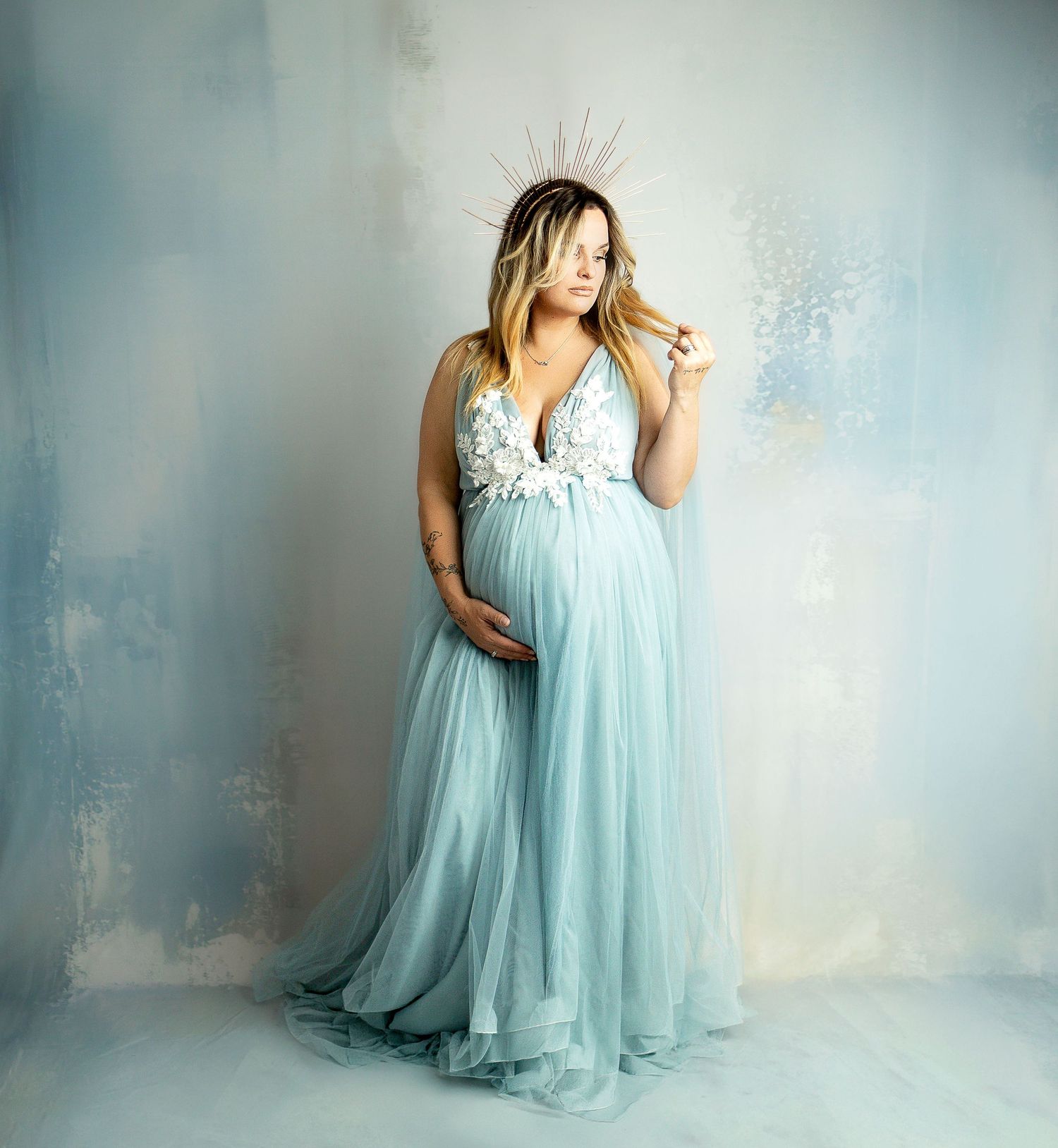 A sage green maxi dress with long sleeves and flowy skirt hangs against a wooden door in three different angles.