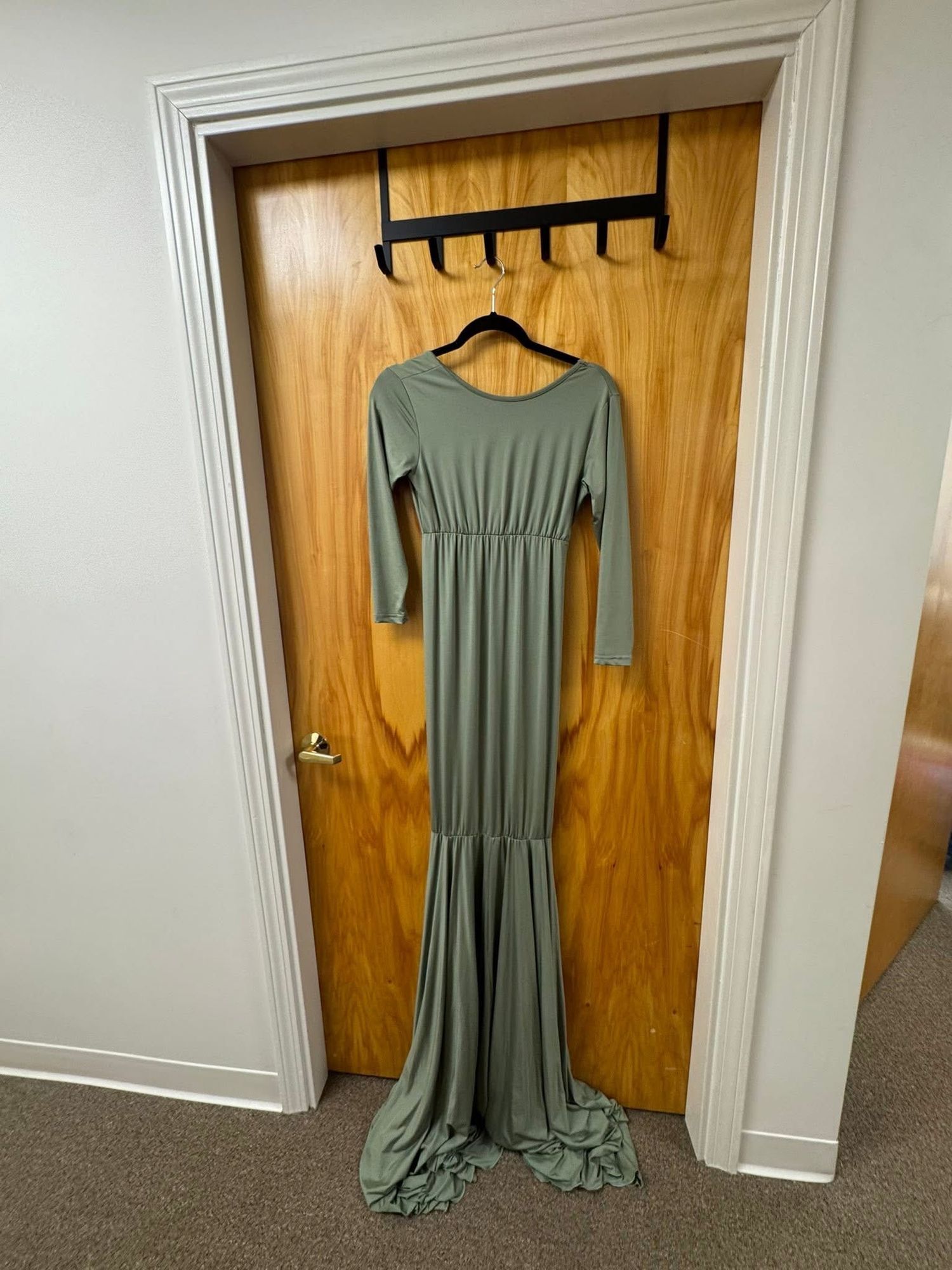 A sage green maxi dress with long sleeves and flowy skirt hangs against a wooden door in three different angles.