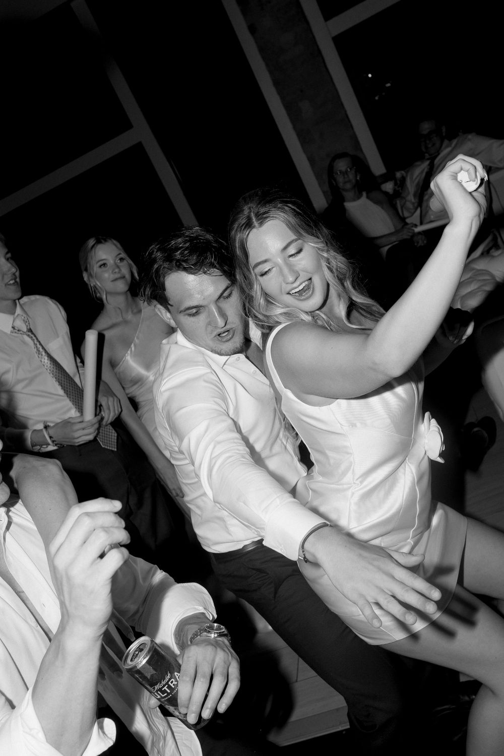 People dancing and celebrating at a wedding reception in black and white photography.