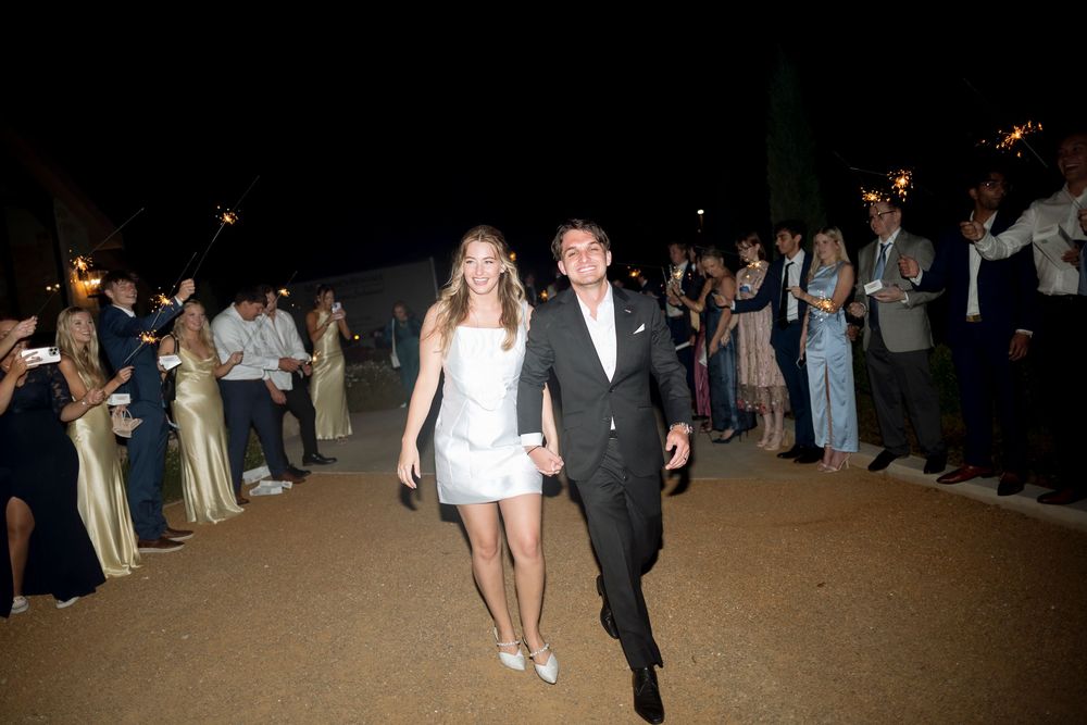 Guests in formal attire walking through a dimly lit venue with people lined up along both sides of the walkway.