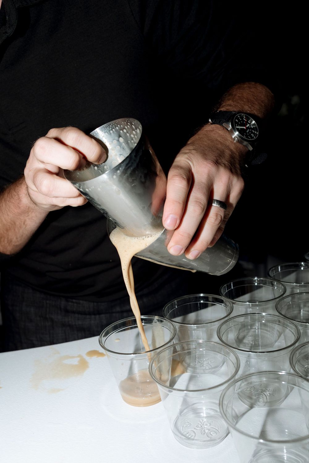 A sequence showing hands pouring coffee or espresso shots into multiple small glass cups in a row.