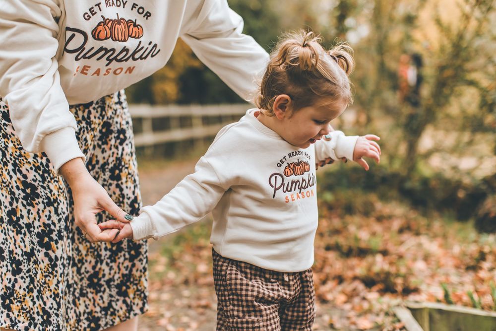 A group of fall family portraits showing people in coordinated cream and brown outfits among autumn leaves.