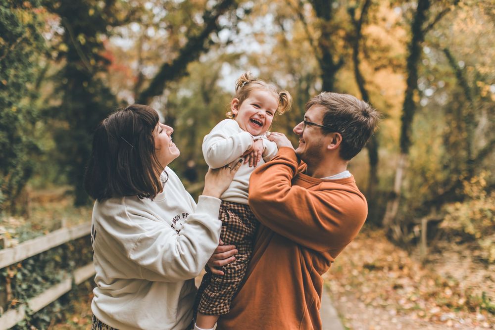 People share joyful moments together while walking on a wooden bridge during fall season.