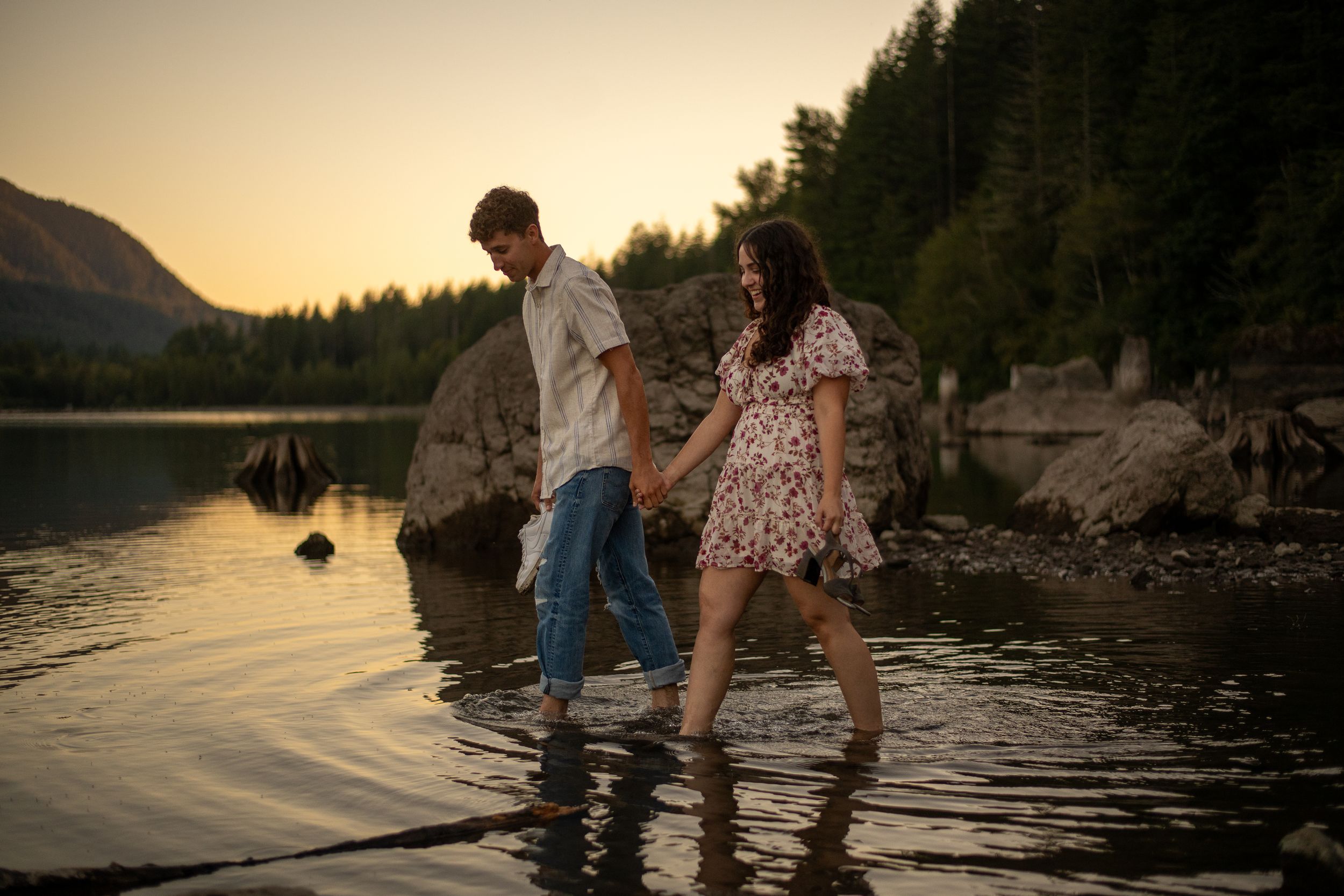 A couple walks through shallow water for their engagement photos at Rattlesnake Lake near North Bend, Washington / Seattle, Washington.