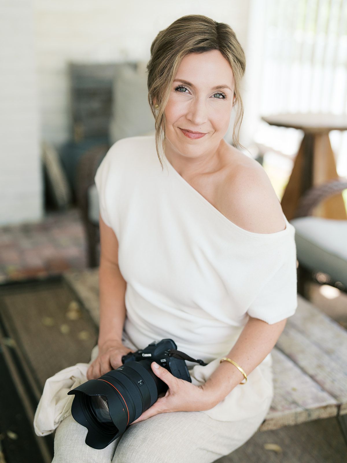 Woman in casual denim and white top poses on gold chair in minimalist studio setting, branding photography Connecticut.