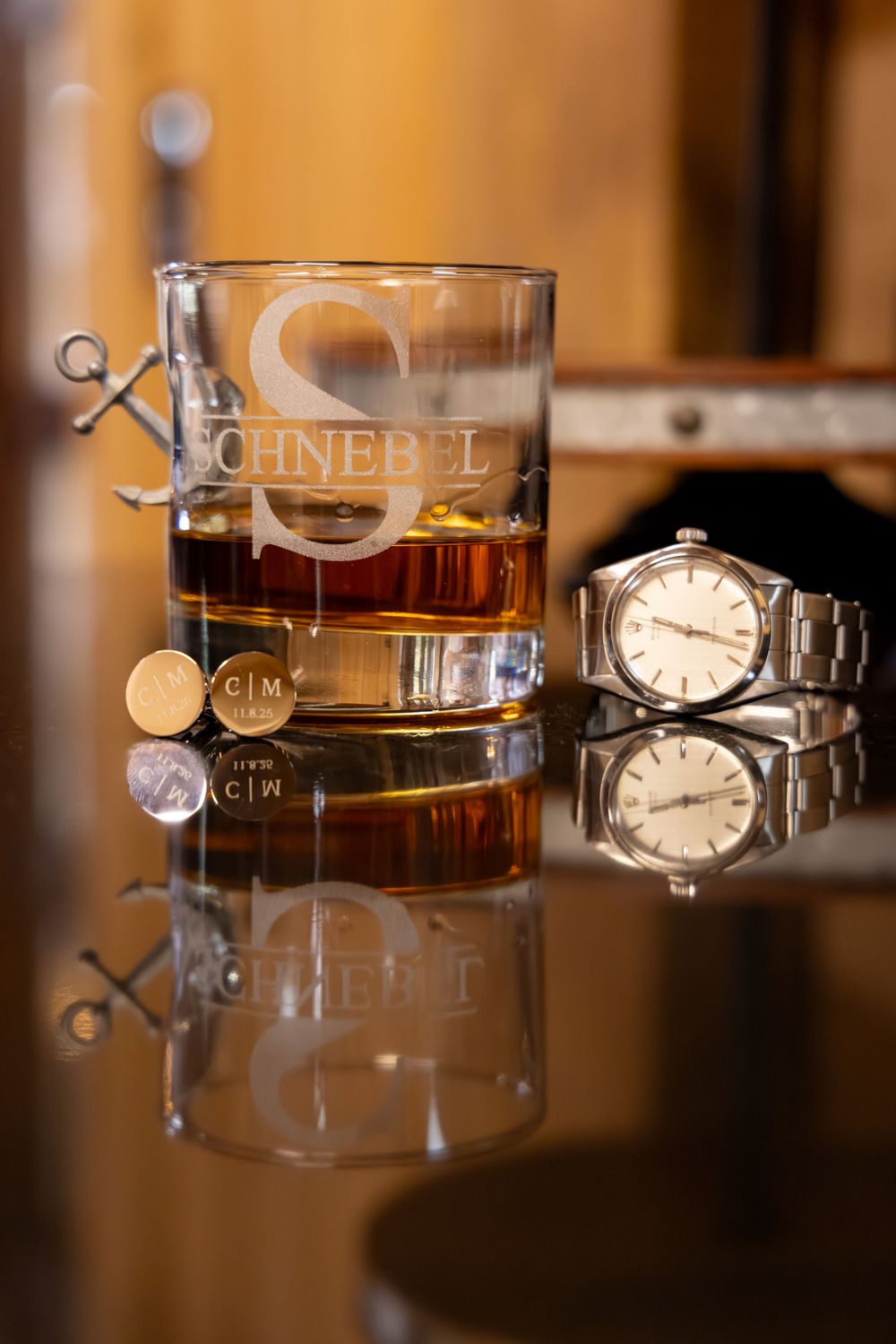 Multiple glasses of whiskey with ice cubes and vintage watches arranged artistically in warm lighting.