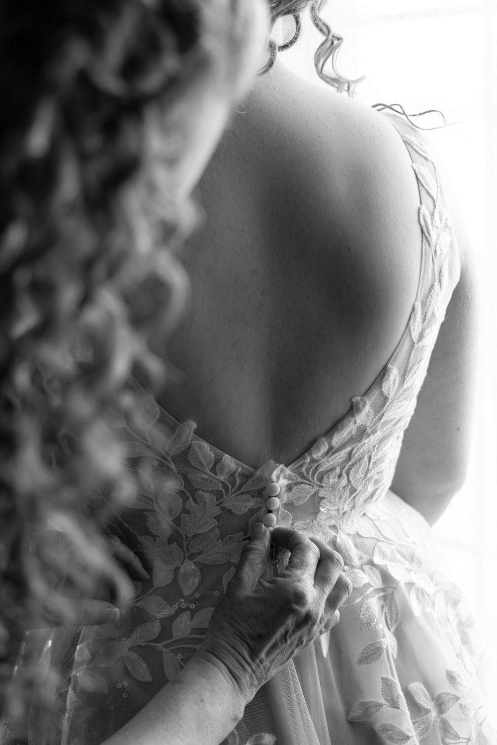 Close-up details of an elegant white lace wedding dress with intricate floral patterns.