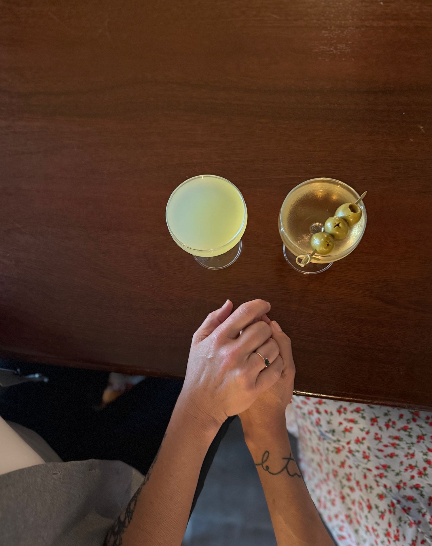 Playing cards and yellow legal pad are arranged on a wooden table with a glass of wine visible in the background.