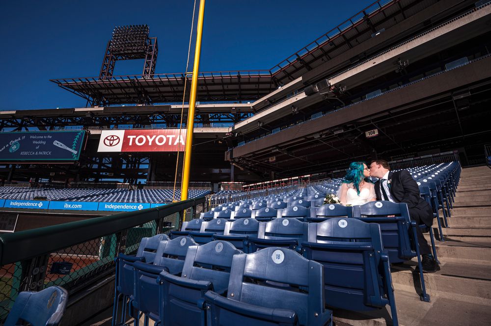 Panoramic view of empty blue stadium seats and yellow foul pole at Citizens Bank Park on a sunny day.